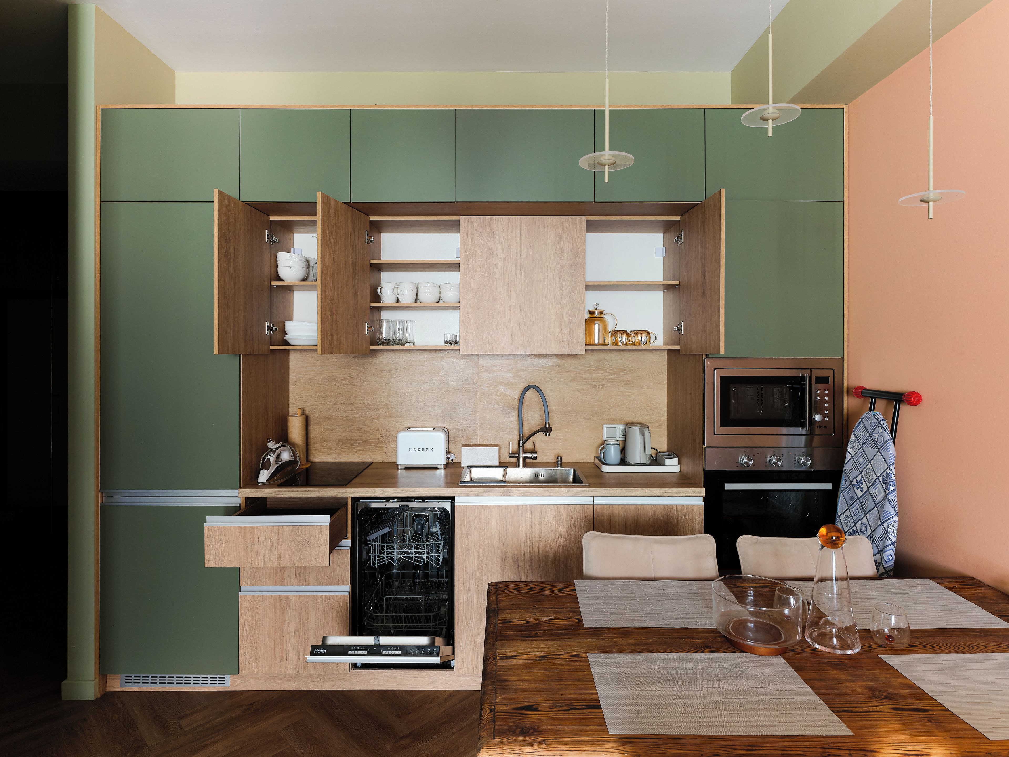 Eine moderne Küche mit Holzschränken, einem eingebauten Geschirrspüler, einer Mikrowelle und einem Essbereich mit einem Holztisch.