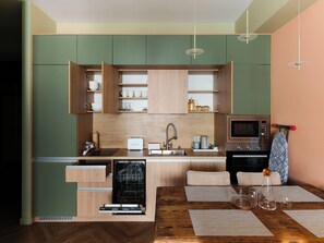 Una cocina moderna con armarios de madera, lavavajillas integrado, microondas y una zona de comedor con mesa de madera.
