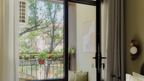 Ein Hotelzimmer mit einer großen Schiebeglasdoor zu einem Außenbalkon mit Pflanzen und einem Stuhl.