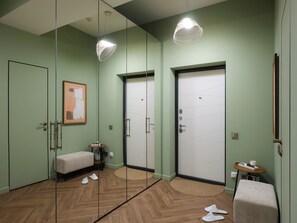 Habitación de hotel con paredes espejadas, un banco, una mesita con una taza y un par de pantuflas en el suelo.