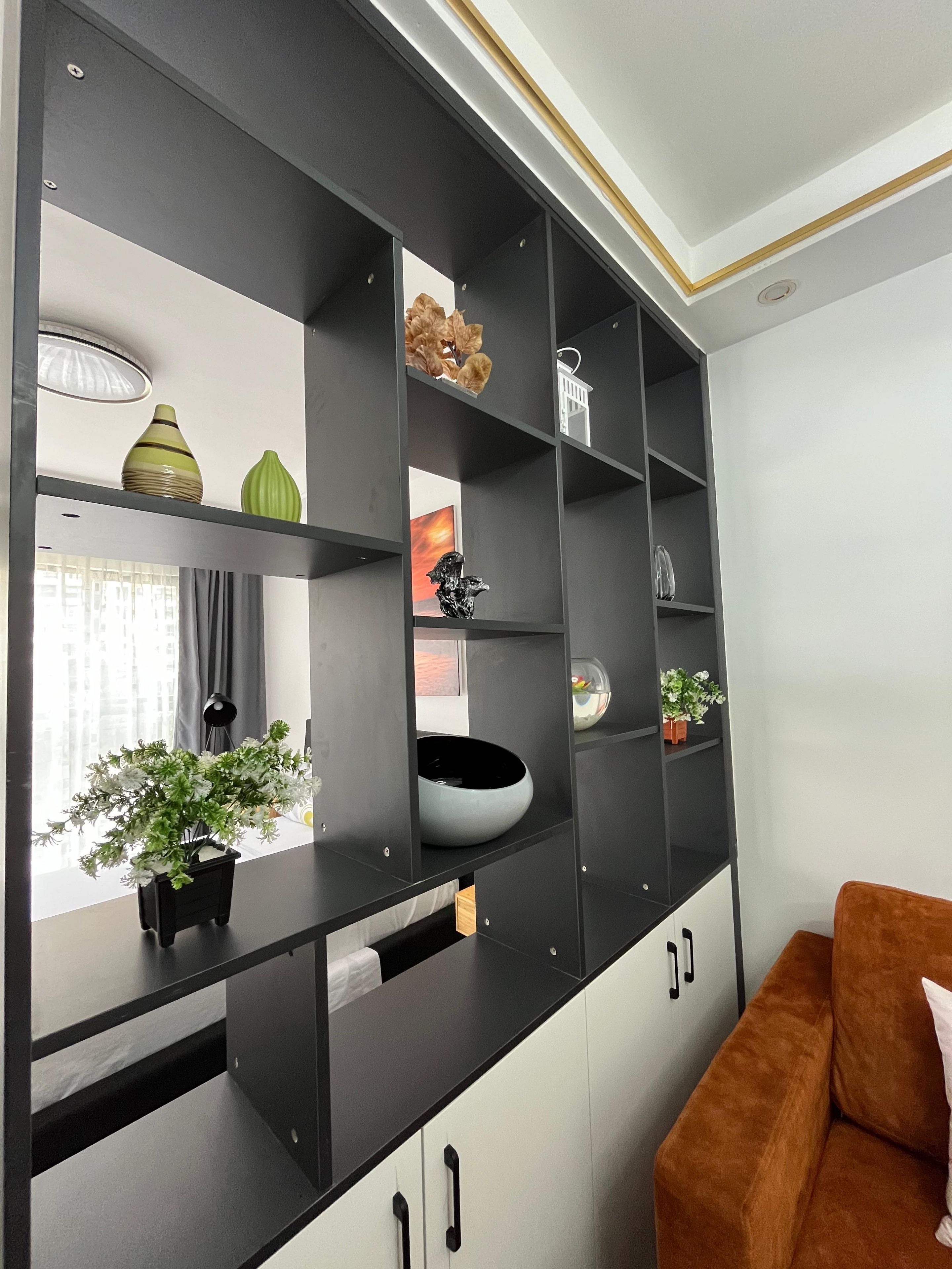 Uma sala de estar moderna com esquema de cores preto e branco, um sofá marrom e um armário preto grande com várias prateleiras.
