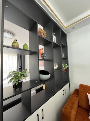 Una sala de estar moderna con una paleta de colores blanco y negro, un sofá marrón y un mueble negro grande con varios estantes.