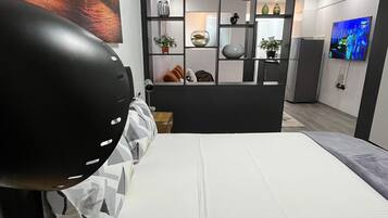 A modern bedroom with a bed, a desk, a TV, and a decorative wall unit.