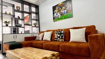 Una sala de estar moderna con un sofá marrón, una mesa de centro de madera y un cuadro colgado en la pared.