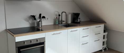 A modern kitchen with a built-in oven, a coffee maker, and a sink.