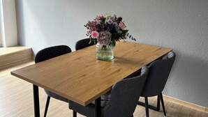 Uma sala de jantar com uma mesa de madeira, quatro cadeiras e um vaso de flores.