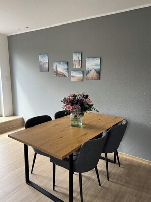 Een eethoek met een houten tafel, vier stoelen en een bloevas.