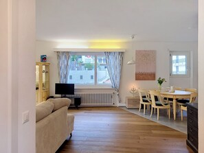 Sala de estar com sofá, TV, mesa de jantar e cadeiras.
