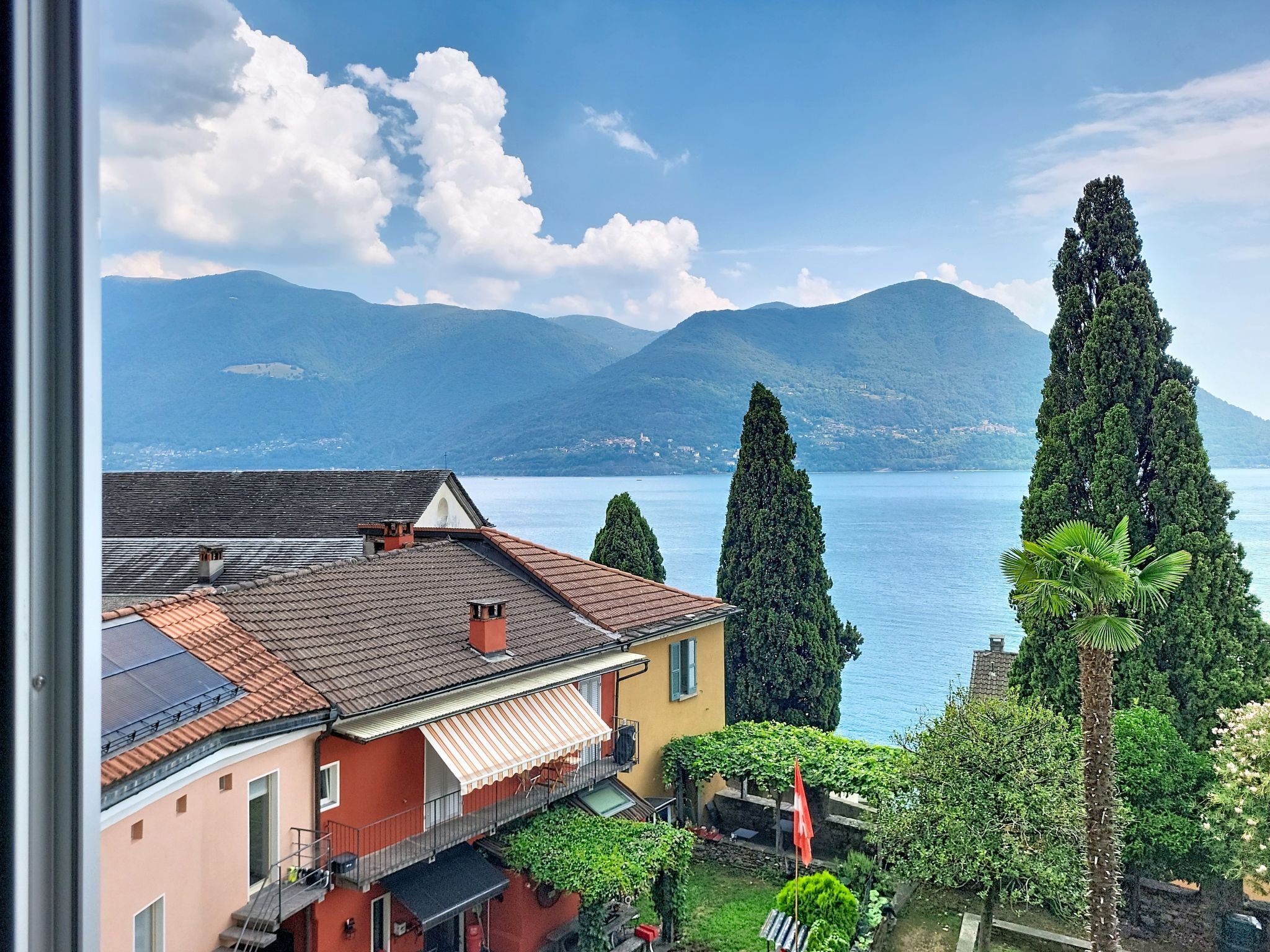 A residential building with a balcony overlooking a lake and mountains.
