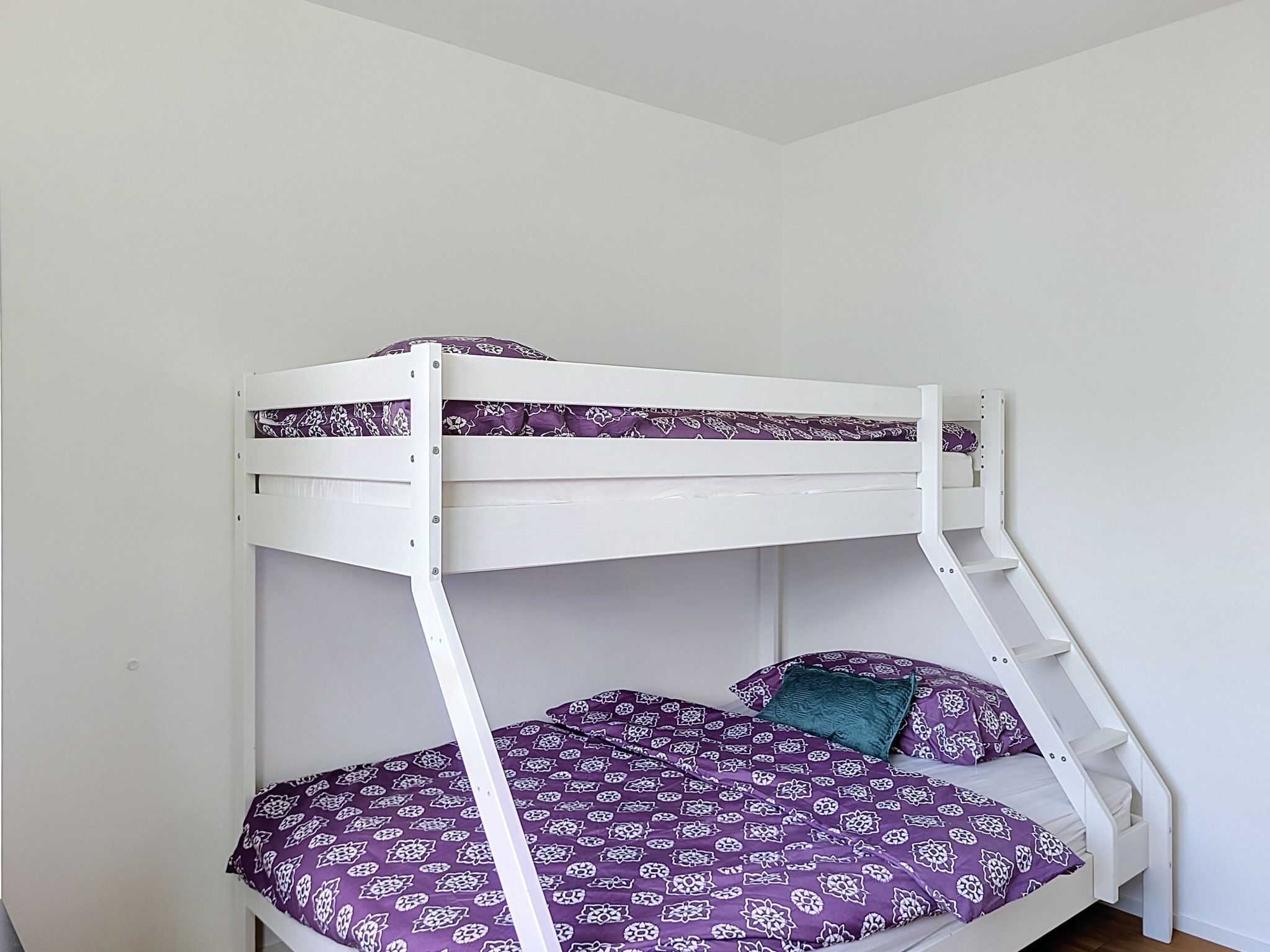 A bunk bed with a ladder, two pillows, and patterned bedding.
