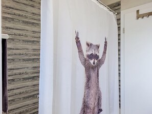 Ein Badezimmer mit einer Duschvorhangs-Illustration eines Waschbären.