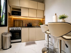 A modern kitchen with a central island, stainless steel appliances, and bar stools. - Cozy 1-bedroom premium studio apartment in delightful Dakar with AC and gym (Dakar)