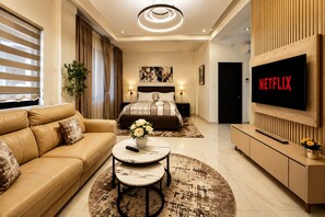 A modern hotel room with a sofa, a bed, a TV, and a coffee table. - Cozy 1-bedroom premium studio apartment in delightful Dakar with AC and gym (Dakar)
