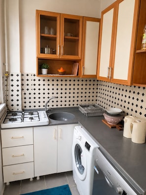 A compact kitchen with a gas stove, sink, and a built-in washing machine. - 3BR Istanbul Apartment In Historic Balat + Golden Horn Views (Istanbul)