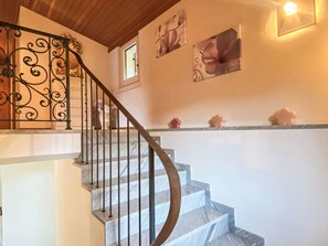 A staircase with a curved handrail and a wall-mounted light fixture. - Casa Matani (Seezugang) by Interhome (Ranzo)