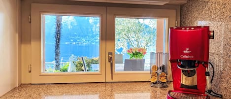 Cozinha com uma cafeteira vermelha, janela com vista para o mar e bancada de granito.