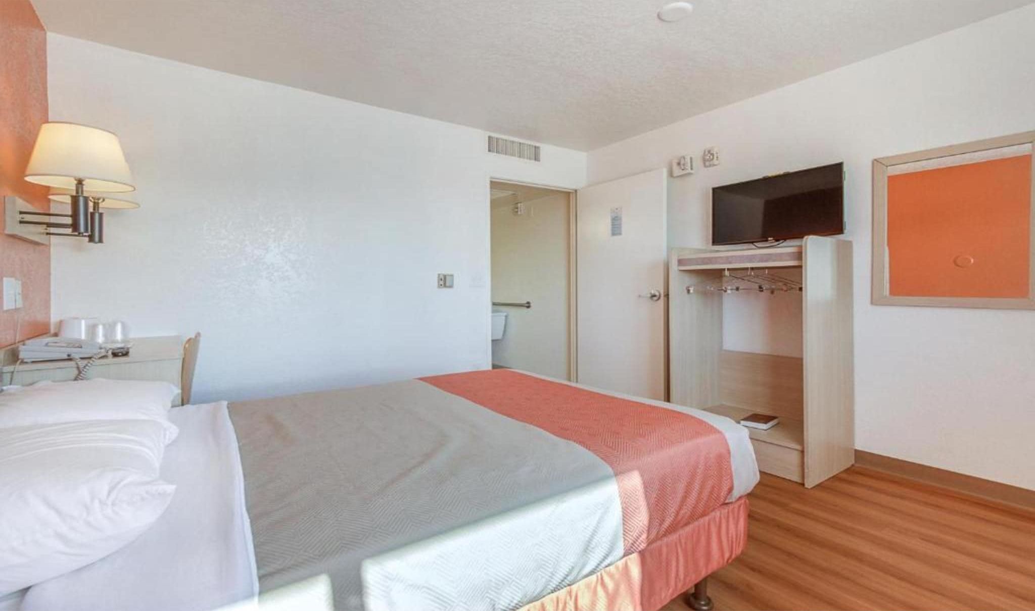 Une chambre d’hôtel comprenant un lit, un bureau avec une lampe, une armoire et un téléviseur.
