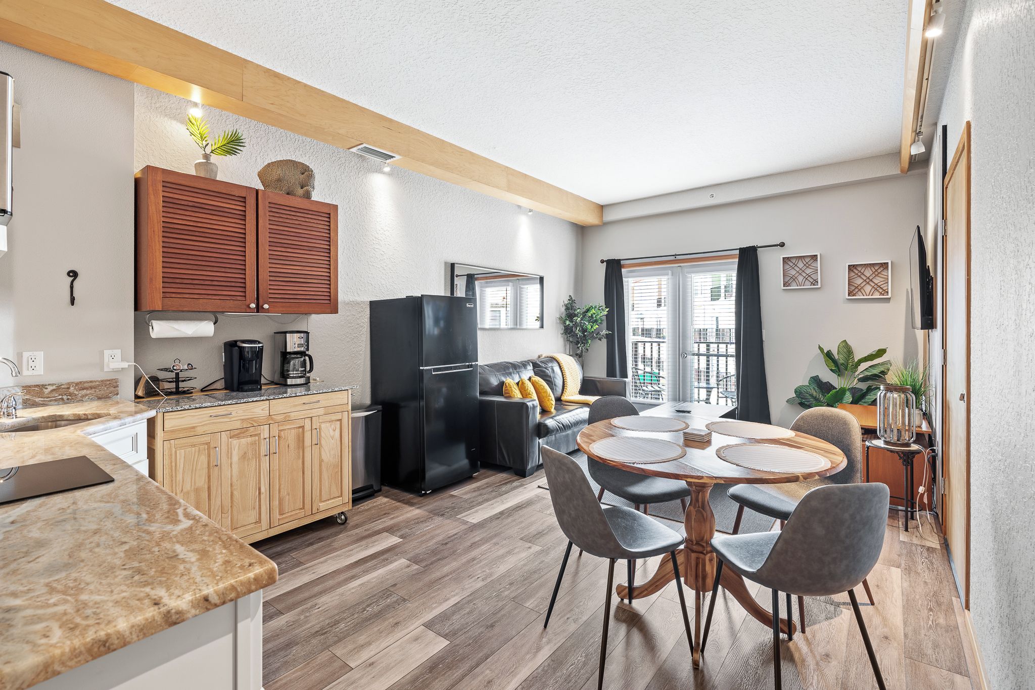 A modern kitchen with wooden cabinets, a refrigerator, and a dining area with a round table and chairs.
