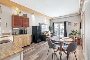 Une cuisine moderne avec des meubles en bois, un réfrigérateur et un coin repas comprenant une table ronde et des chaises.