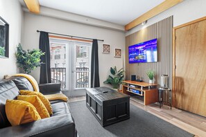Un salon moderne comprenant un canapé, une table basse, un téléviseur et une porte coulissante donnant sur un balcon.