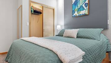 A bedroom with a bed, a wardrobe, a painting, and a lamp.