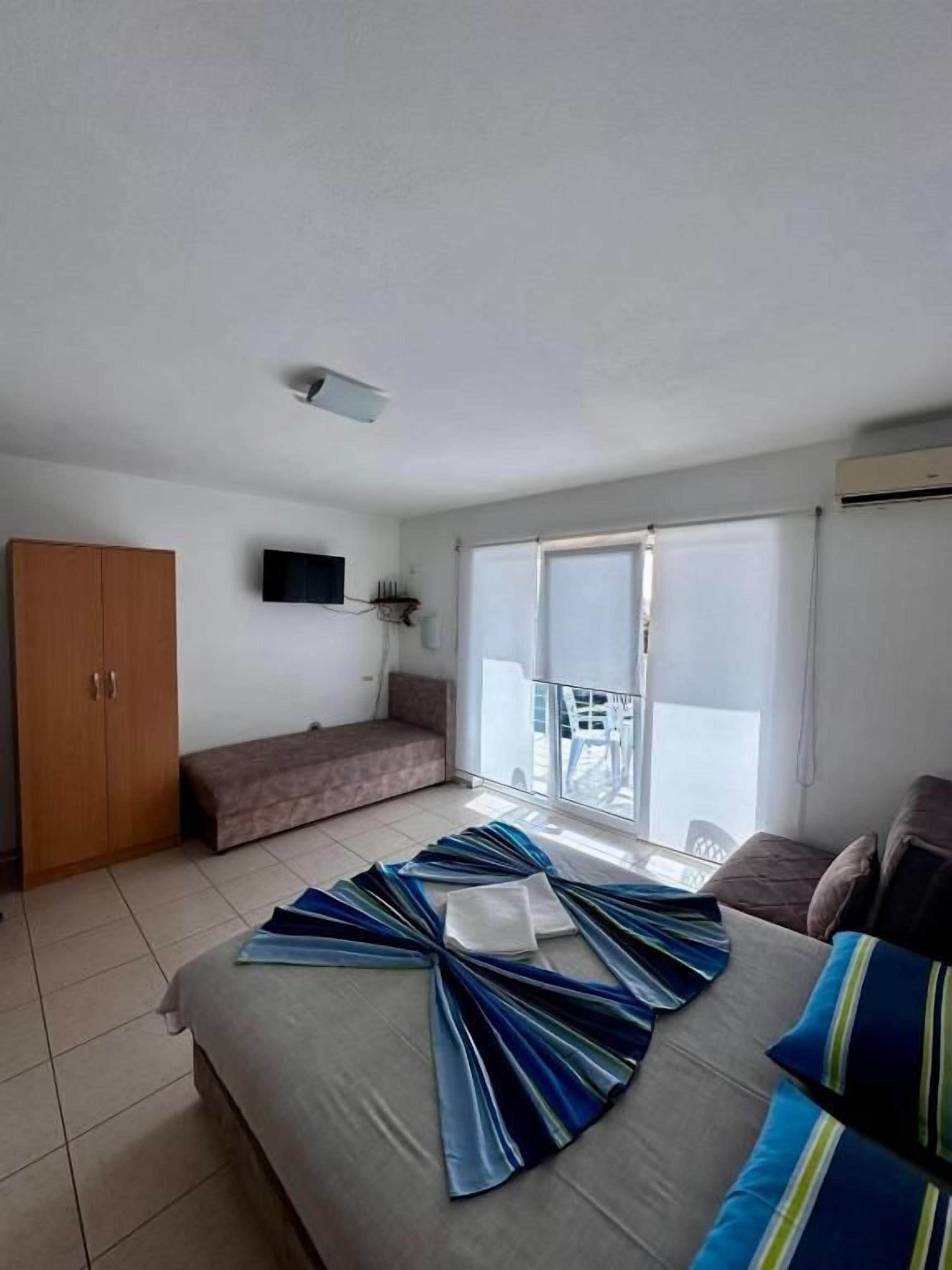 Une chambre d’hôtel avec un lit, une banquette, une armoire, une télévision et un balcon offrant une vue.