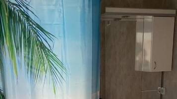 A bathroom with a shower curtain depicting a beach scene, a sink, and cabinets.