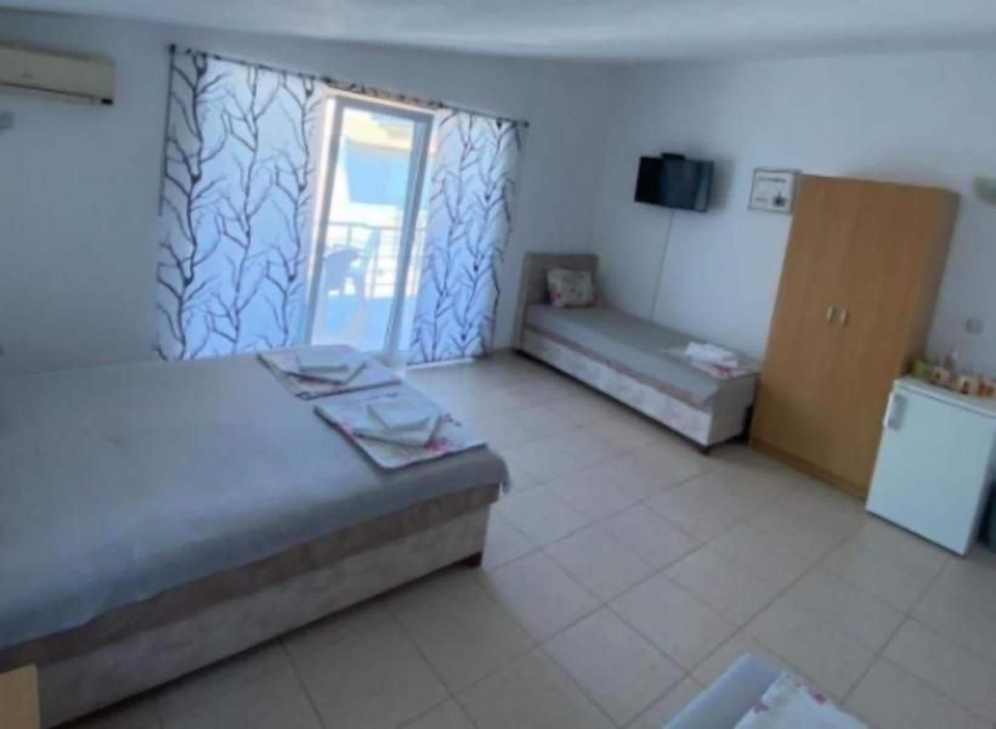A room with a bed, a small sofa, a cabinet, and a television on the wall.