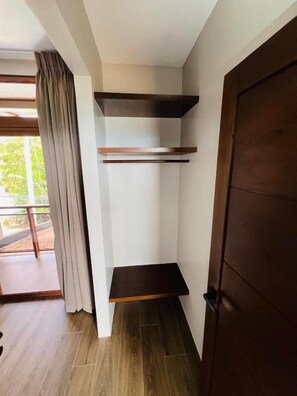 A room with a wooden door, a window with curtains, and a built-in shelf unit.