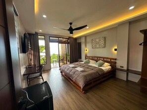 Une chambre moderne avec un grand lit, un ventilateur de plafond et une vue sur l’extérieur.