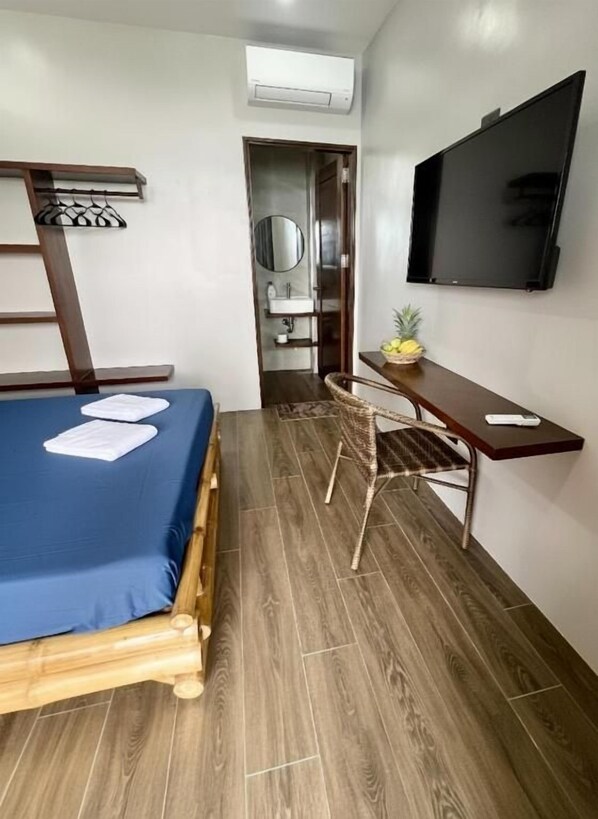 A compact room with a bed, a desk, a chair, a television, and a small bathroom.