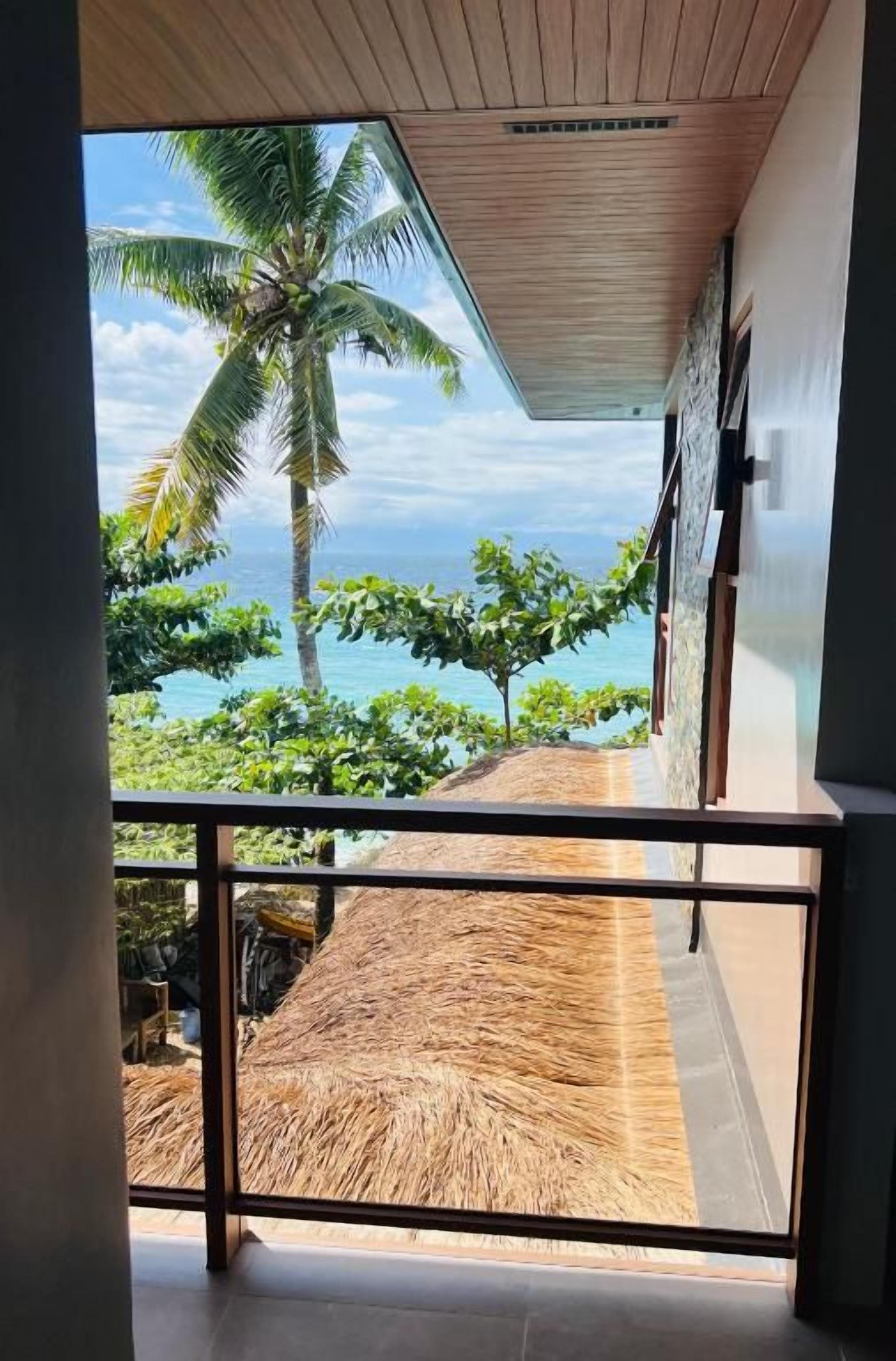 Un balcón con vistas a una playa y palmeras.