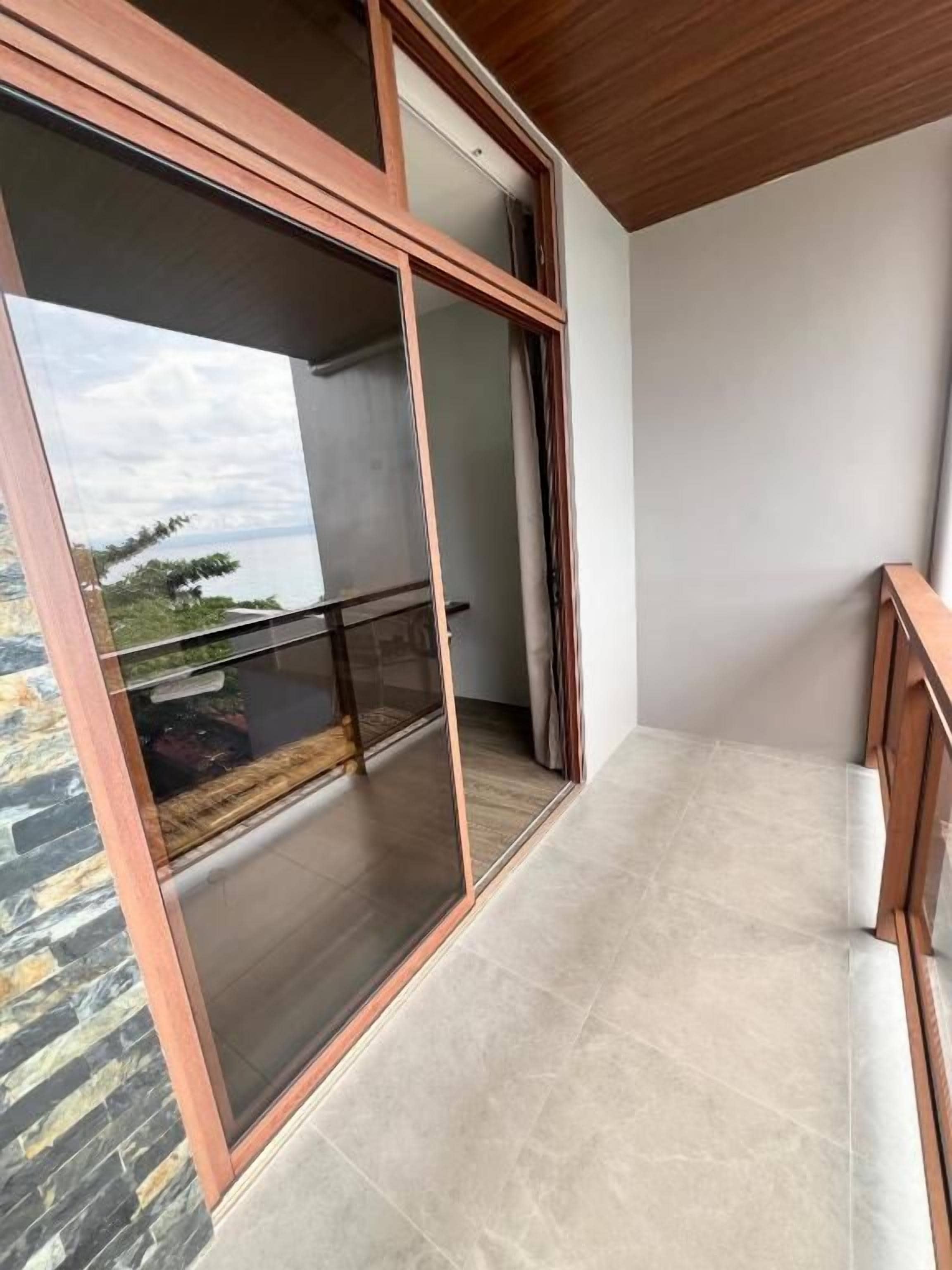 Un balcón con puerta de vidrio, vista al cielo y suelo de baldosas.