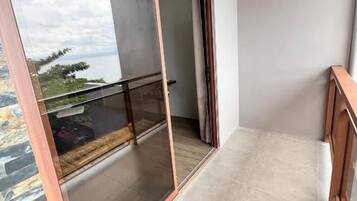 Un balcón con puerta de vidrio, vista al cielo y suelo de baldosas.