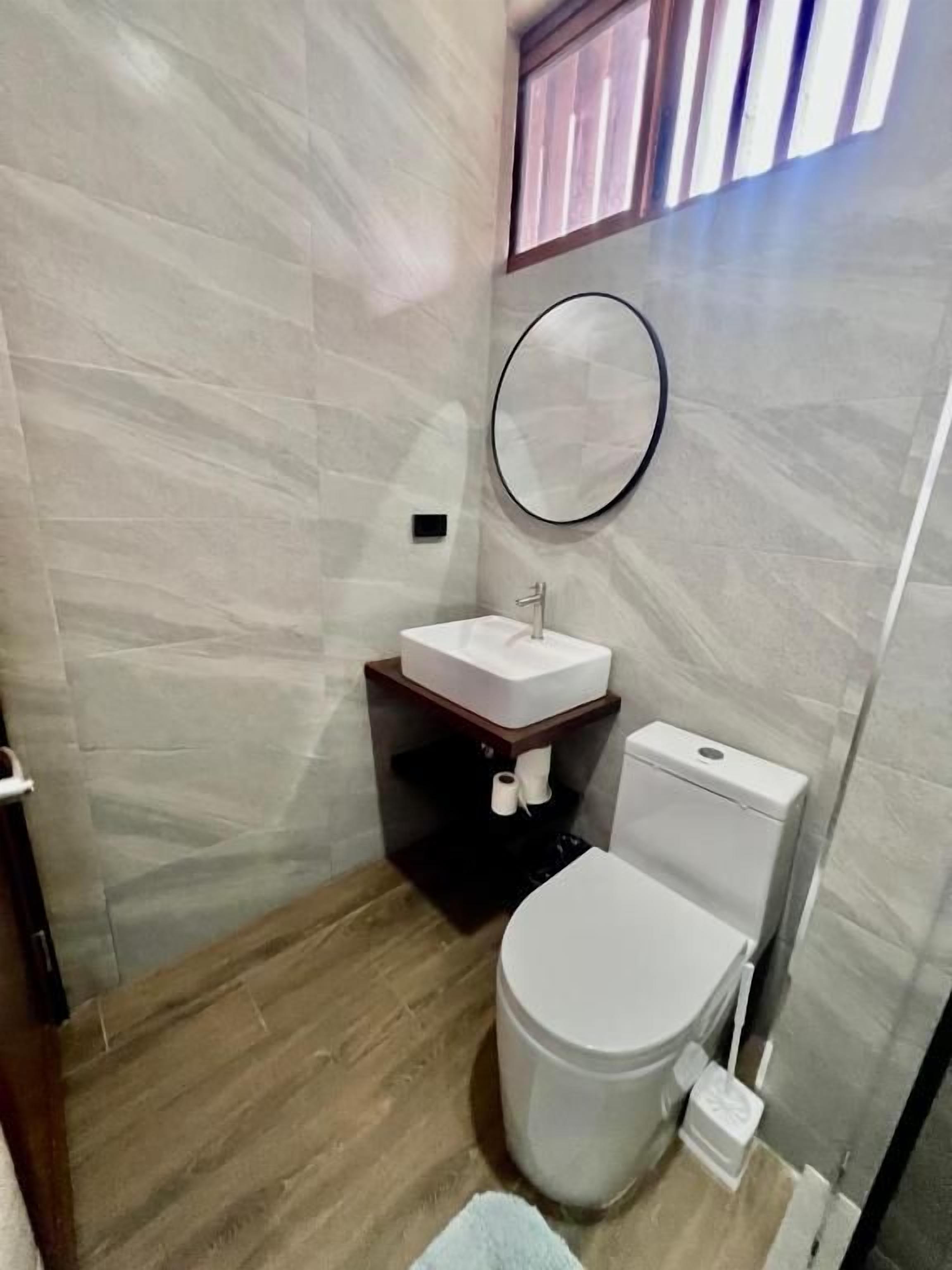 A small bathroom with a toilet, sink, and mirror.