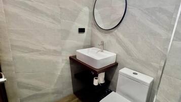 A small bathroom with a toilet, sink, and mirror.