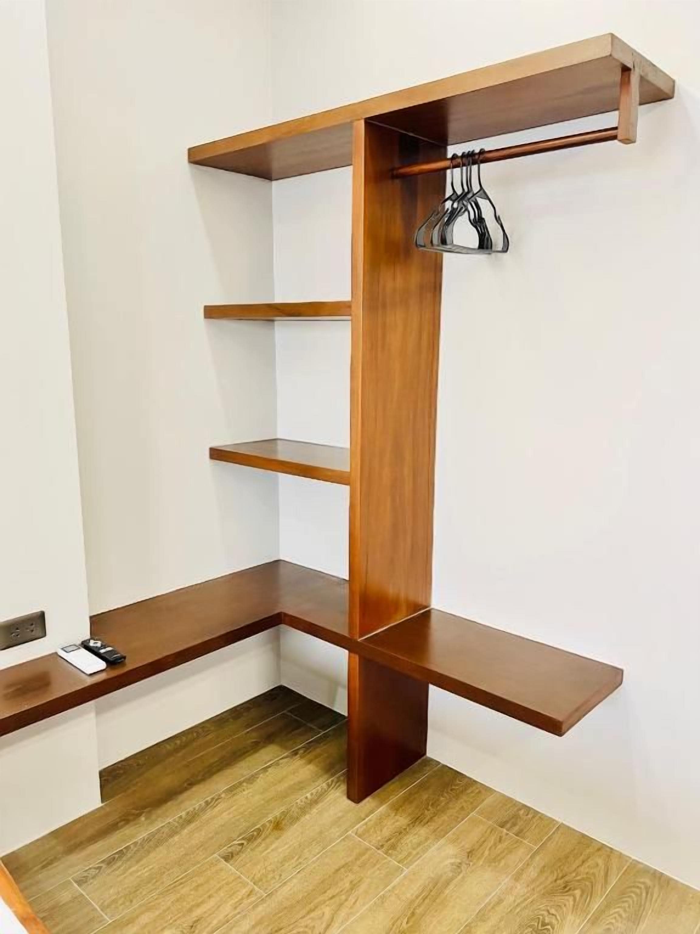 Una habitación de esquina con una estantería empotrada de madera, un perchero y una mesita.
