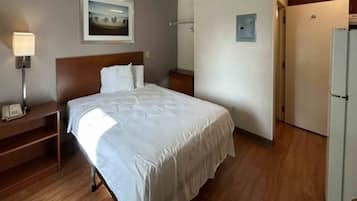 Une chambre d’hôtel comprenant un lit, une table de chevet, une lampe et une porte donnant accès à une salle de bain.