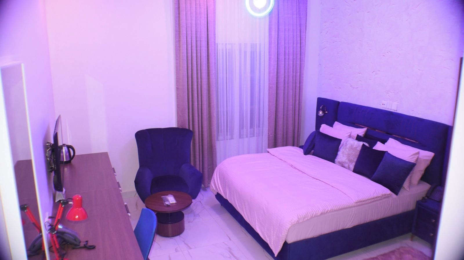 Una habitación de hotel con una cama, una silla, un escritorio y una mesita.