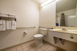 Ein Standard-Hotelbad mit Toilette, Waschbecken und Haltegriffen.