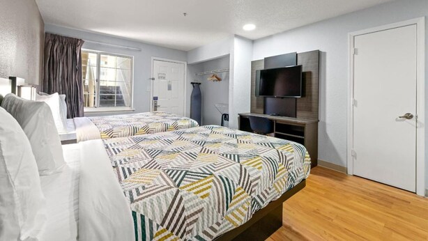 A hotel room with two beds, a TV, a wardrobe, and a window with curtains. - 2 Queen bed|Non Smoking (Duluth)