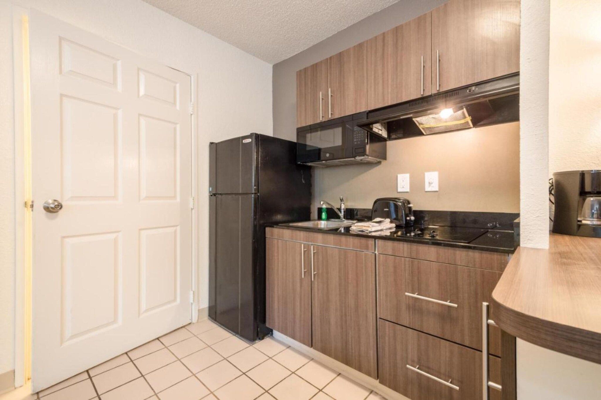 A compact kitchen with a refrigerator, microwave, and a coffee maker on the counter.