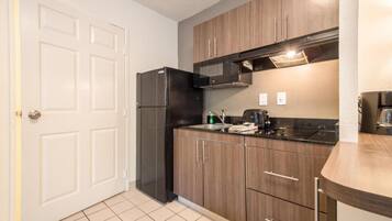 A compact kitchen with a refrigerator, microwave, and a coffee maker on the counter.