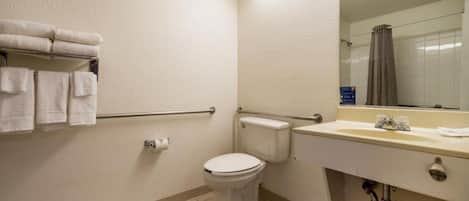 A bathroom with a toilet, sink, and handrails.