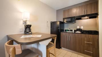 A compact kitchenette with a coffee maker, refrigerator, microwave, and a small countertop.