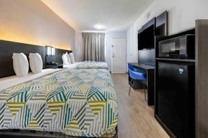 Ein Hotelzimmer mit einem Bett, einem Schreibtisch, einem Stuhl, einem Fernseher und einem Kühlschrank.