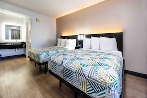 Ein Hotelzimmer mit zwei Betten, einem Badezimmer und einem Nachttisch mit Lampe.