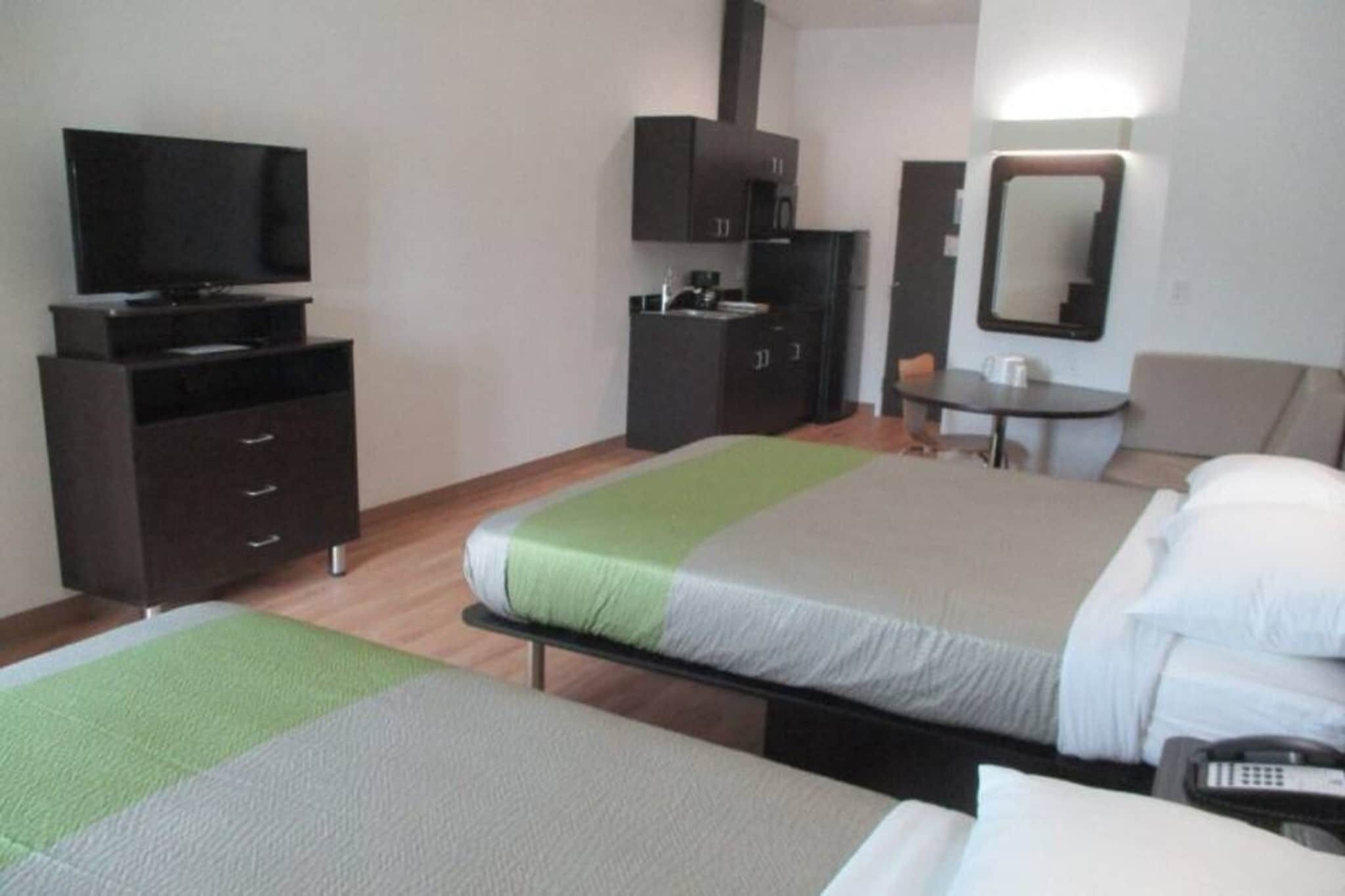 A hotel room with two beds, a desk, a chair, a television, and a wardrobe.
