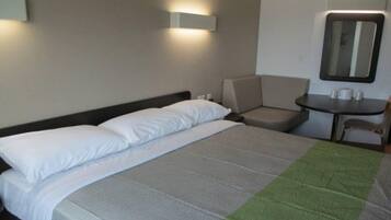 Une chambre d’hôtel avec un lit, une chaise, une petite table et un miroir.