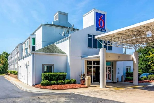 Um hotel de 6 andares com design moderno, entrada coberta e área de estacionamento.
